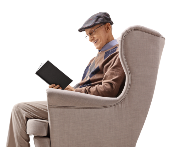 Happy Senior Man Sitting In Wing-back Chair Reading A Book